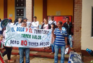 A group of demonstrators hold a sign protesting an oil project in Colombia.