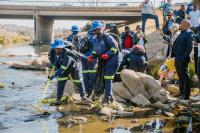 A group of people removes trash from a river.