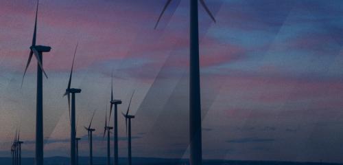 Windmills are framed by a pink and blue sky