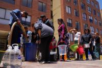 People stand in line with buckets for water rations.