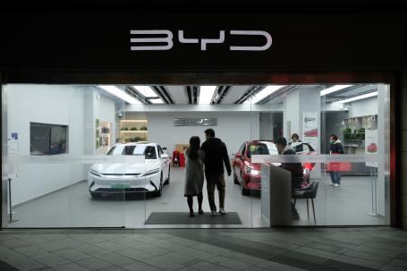 A couple walks into a car showroom with a sign that reads BYD.