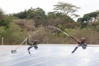 Two men clean solar panels in Kenya