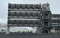 Direct air capture units at a Climeworks facility in Iceland with snow-capped mountains in the background.