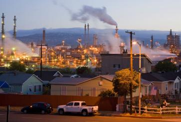 A neighborhood sits in front of an oil refinery. 