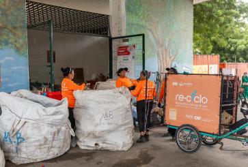 People handle large bags of recyclables outside a waste collection center.