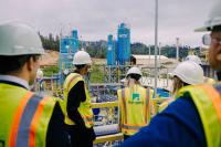 People wearing construction vests and hard hats look out at the Fortera cement plant.