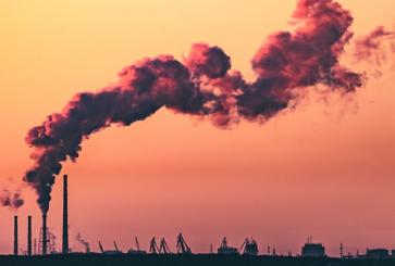Emissions rising from a factory with a sunset in the background. 