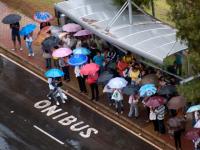People wait under umbrellas at a bus stop in Brazil