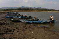 An Indonesian fisherman prepares a boat in the drying Gajah Mungkur Reservoir