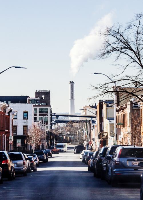 Smokestacks in the background of a neighborhood with rowhouses in Baltimore, MD
