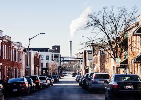 Smokestacks in the background of a neighborhood with rowhouses in Baltimore, MD
