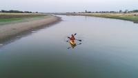 Two people in a kayak paddle down the Kham River in India.