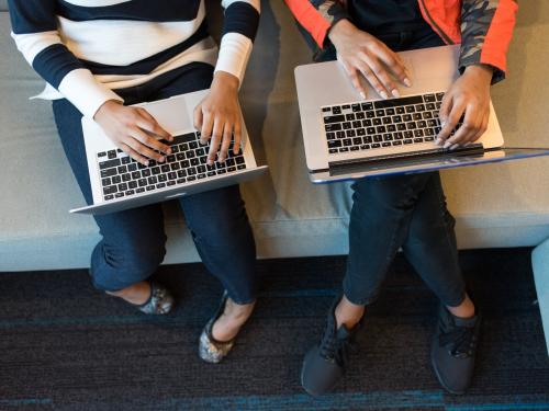two people's hands working on laptops