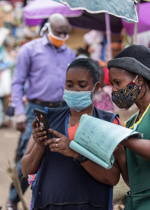 Women wearing face masks looking at phone.