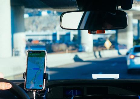 A driver following GPS directions on a mounted smartphone, taken from the backseat of the car.