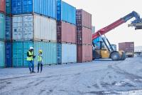 Workers standing in front of shipping containers.
