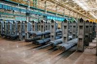 Bundles of steel bars stacked on shelves on a large storeroom floor. 