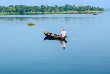 A man in a boat on a body of water in Chittagong, Bangladesh