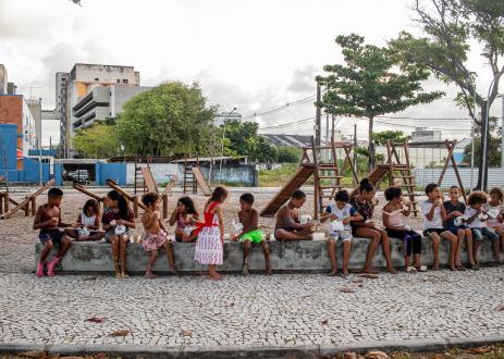 A group of children of various ages sitting together on a cement bench in Recife, Brazil.