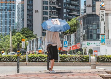 Woman walking wearing covering for heat and umbrella.