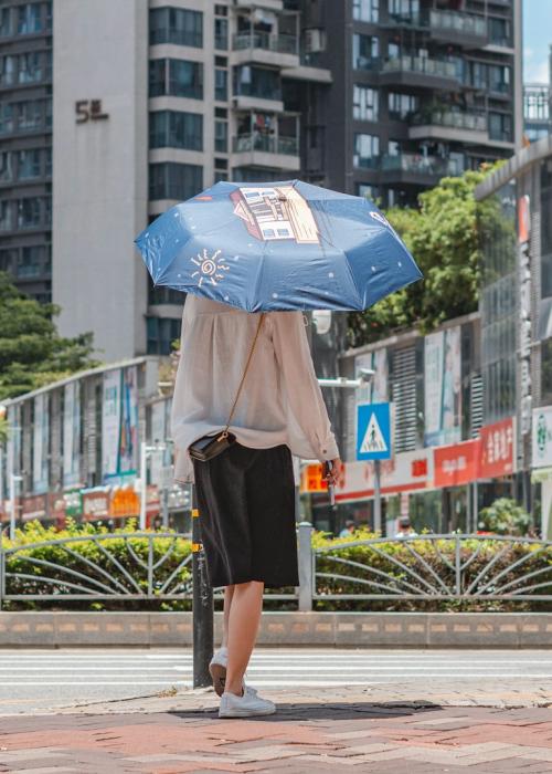 Woman walking wearing covering for heat and umbrella.