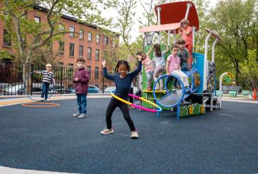 Children enjoy the vibrant new playground in the recently redesigned green schoolyard at P.S. 38K in New York, where fresh equipment and engaging spaces foster creativity and play.